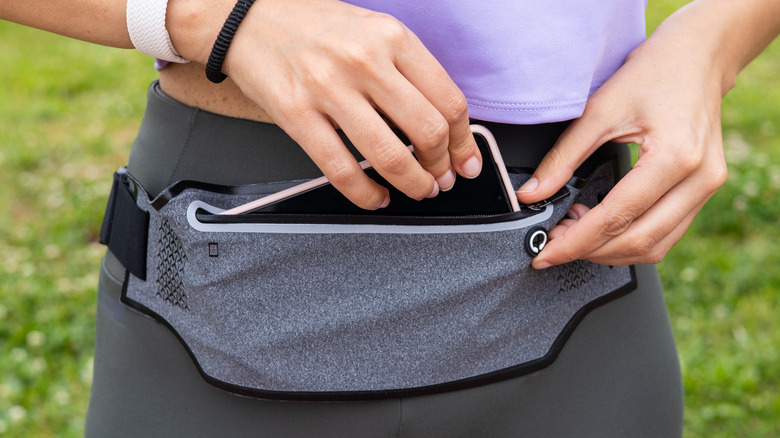 woman placing iPhone in belt bag